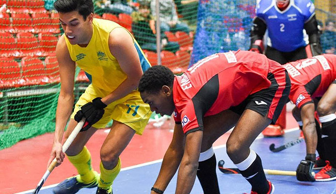 Trinidad and Tobago’s Kristien Emmanuel (centre) tries to get the ball from Australia’s Jake Sherren (left) during yesterday’s match in the FIH Indoor Hockey World Cup in Berlin, Germany. Also in photo are TT’s captain Solomon Eccles (right) and goalkeeper Ron Alexander. PHOTO COURTESY FIH.