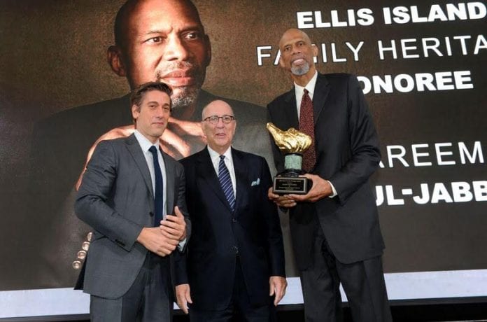 Basketball legend Kareem Abdul-Jabbar (right) receives the 2017 Ellis Island Family Heritage Award from host David Muir ( left), anchor and managing editor of ABC World News Tonight, and Stephen Briganti, president and CEO, Statue of Liberty-Ellis Island Foundation. The occasion took place October 24, 2017 at Ellis Island in New York. Photo credit: Diane Bondareff/Invision for Statue of Liberty-Ellis Island.